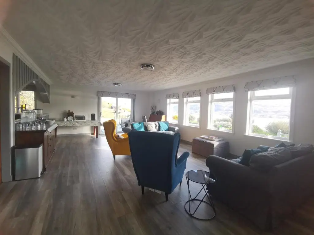 a living room with two couches and a kitchen at Lochbroom Lodge in Ullapool
