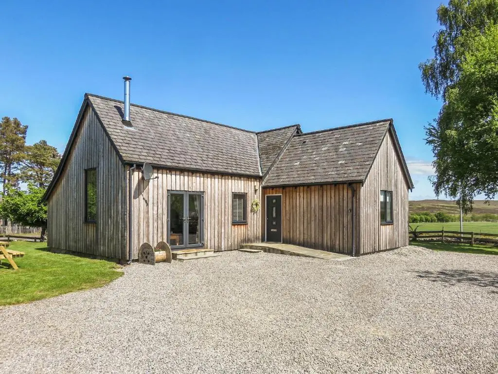 a large wooden barn with a gravel driveway at Old School House in Altnaharra