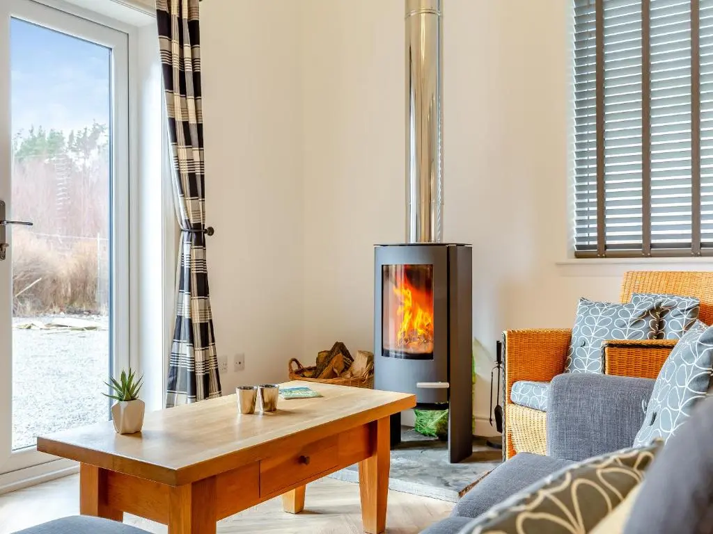 a living room with a fireplace and a table at Old School House in Altnaharra