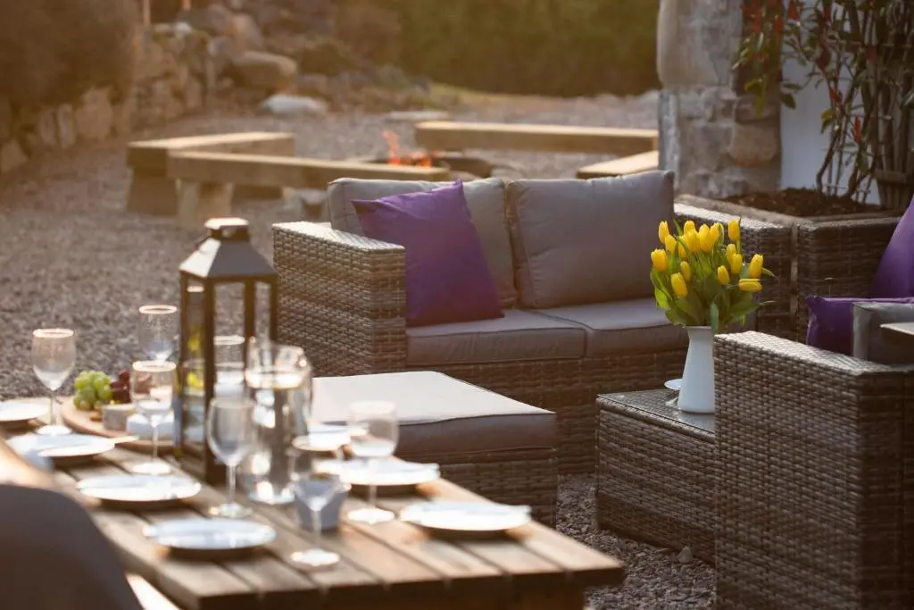 a wooden table with a couch and flowers on a patio at The Wilds - Seasgair Lodges in Kingussie