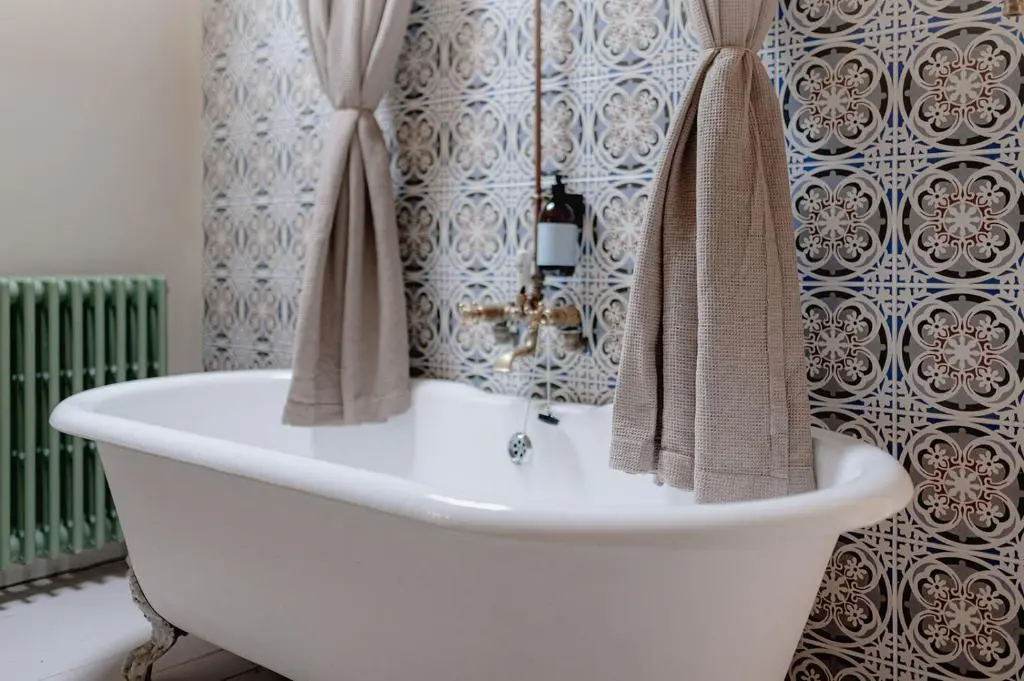 a bathroom with a bath tub with towels on a wall at The Dell of Abernethy - A Woodland hideaway in Nethy Bridge