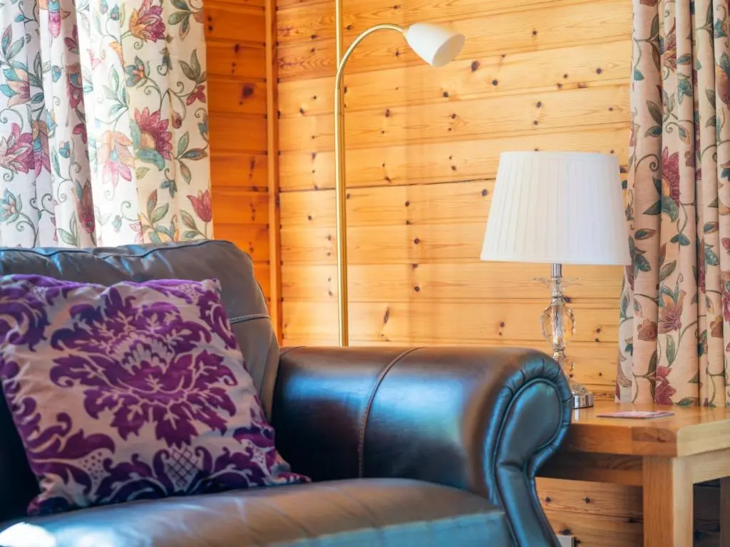 a leather chair sitting next to a table with a lamp at Holiday Home Achmony Number 9 by Interhome in Drumnadrochit
