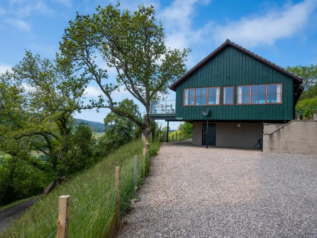 a house with a green roof and a gravel driveway at Holiday Home Achmony Green by Interhome in Drumnadrochit