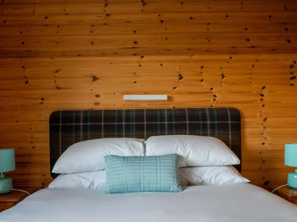 a bedroom with a bed with a wooden wall at Holiday Home Achmony Byre by Interhome in Drumnadrochit
