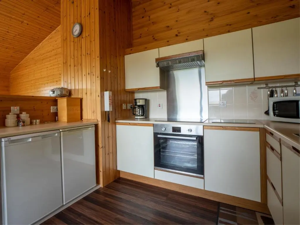 a kitchen with white appliances and wooden walls and wooden floors at Holiday Home Achmony Byre by Interhome in Drumnadrochit