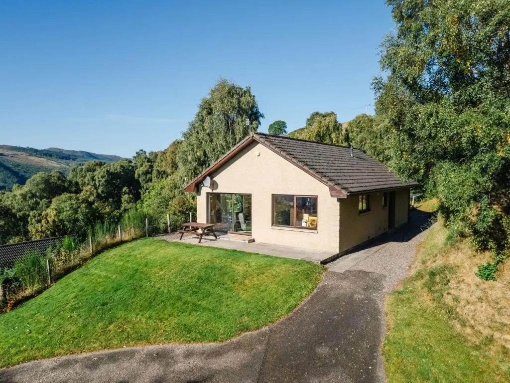a small white house with a grassy yard at Holiday Home Achmony Number 10 by Interhome in Drumnadrochit