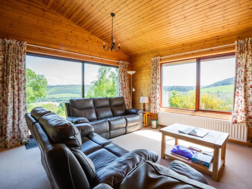 a living room with a leather couch and large windows at Holiday Home Achmony Number 10 by Interhome in Drumnadrochit
