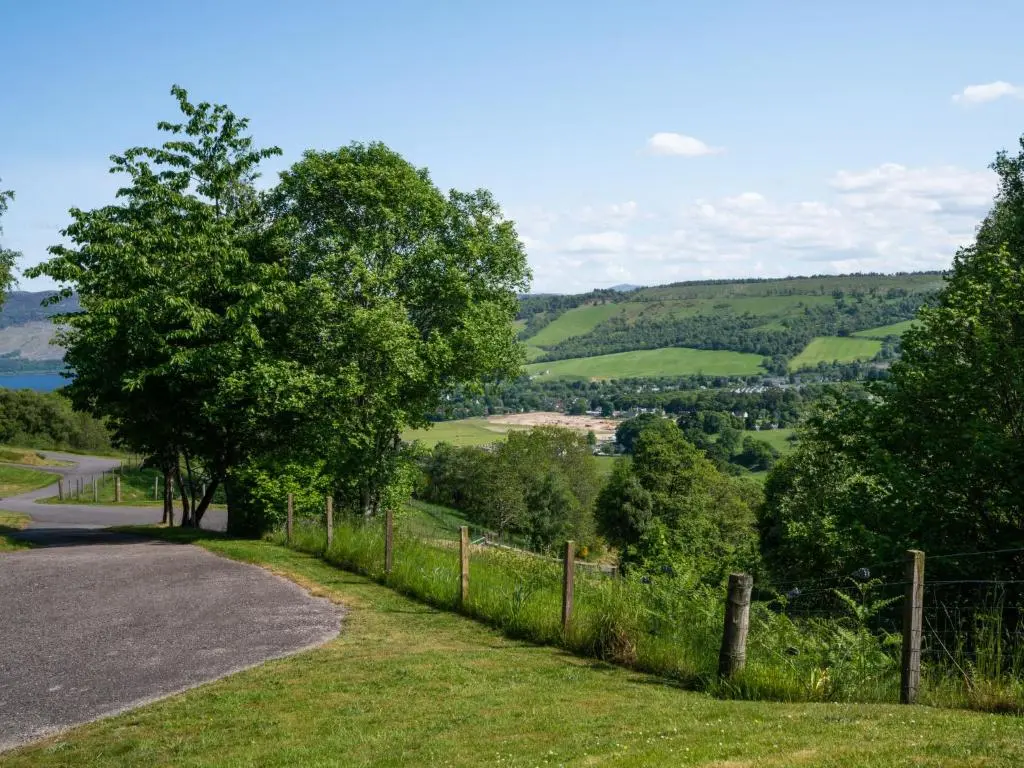 a road with a fence and trees on a hill at Holiday Home Achmony Number 10 by Interhome in Drumnadrochit