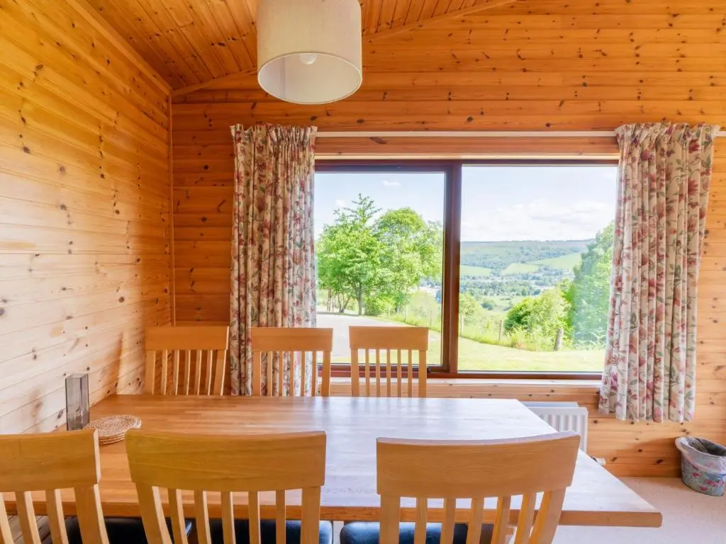 a dining room with a table and chairs and a large window at Holiday Home Achmony Number 10 by Interhome in Drumnadrochit