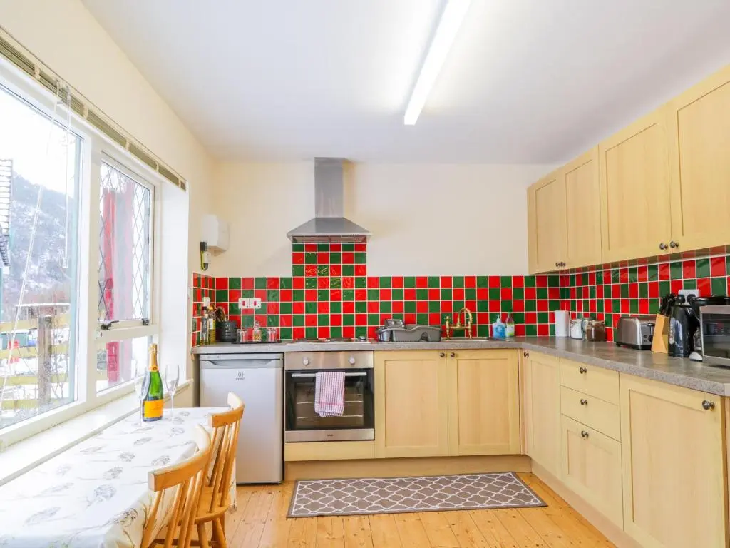 a kitchen with a table and a red and green tiled wall at The Old Mill in Beauly