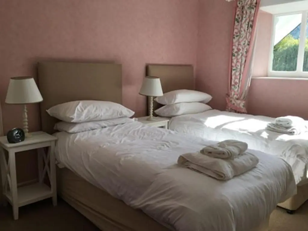 two beds in a bedroom with two lamps and towels at The Delnashaugh in Ballindalloch