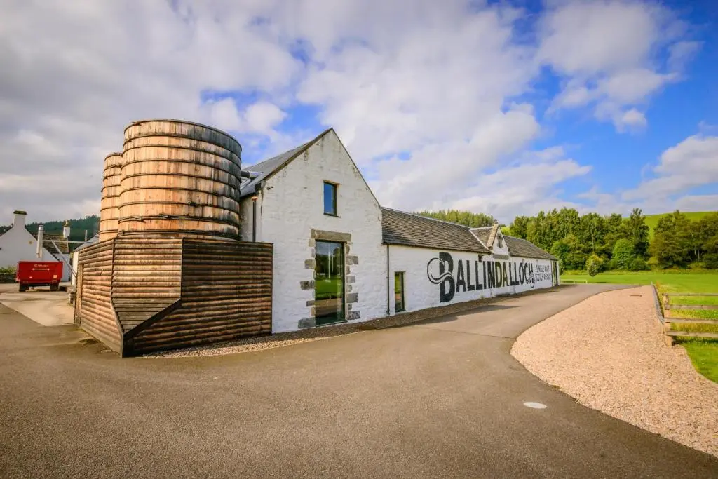a white building with a silo next to a road at The Delnashaugh in Ballindalloch