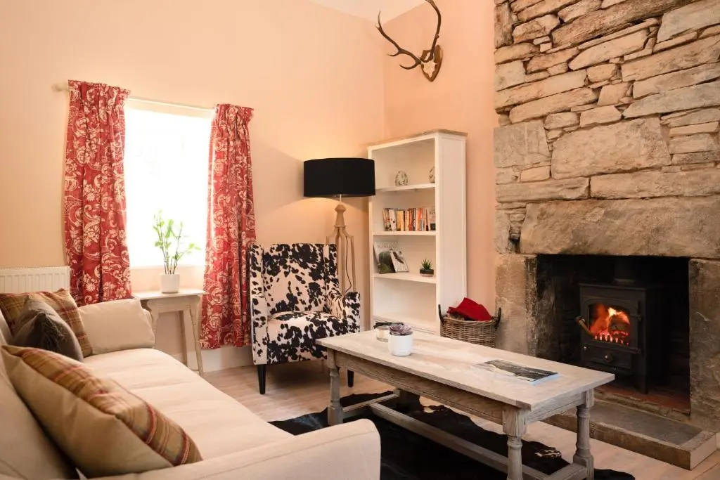 a living room with a fireplace and a table at Kincraig House - Seasgair Lodges in Kincraig
