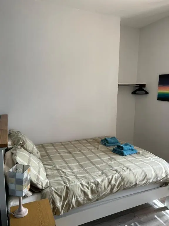 a bed in a room with a white wall at Rosebery apartment-Inverness in Inverness