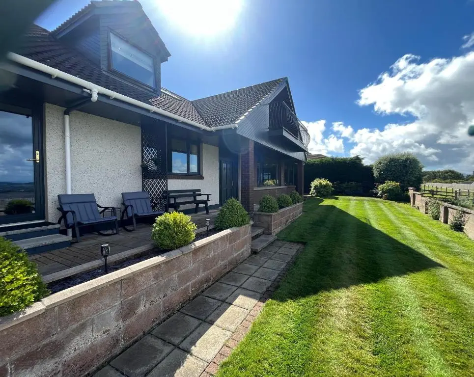 a house with a patio and a lawn at Bonny Vista in Inverness