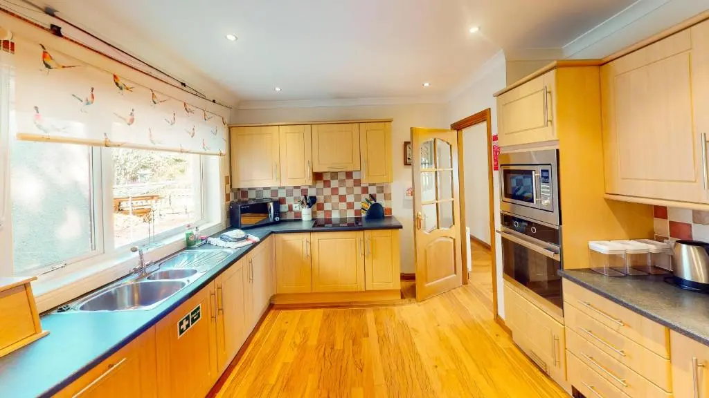 a kitchen with wooden cabinets and a sink and a window at The Shieling in Aviemore