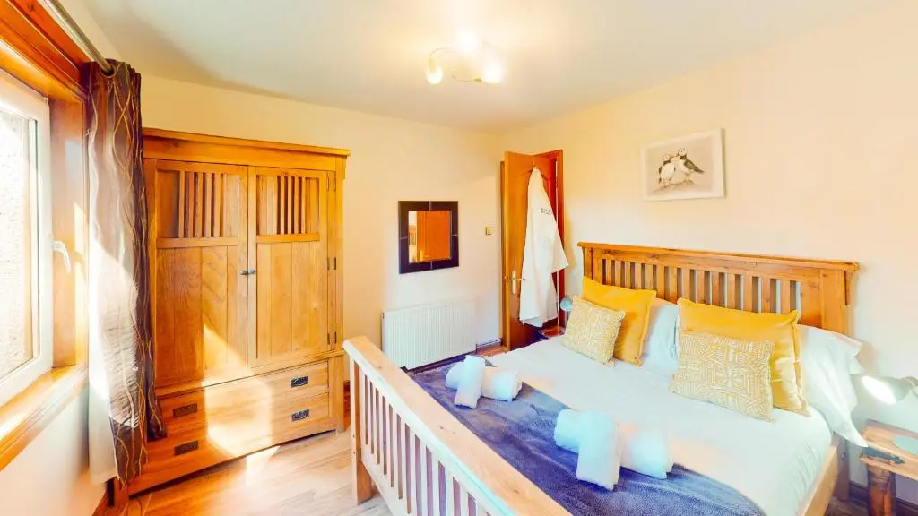 a bedroom with a wooden bed with yellow pillows at The Shieling in Aviemore