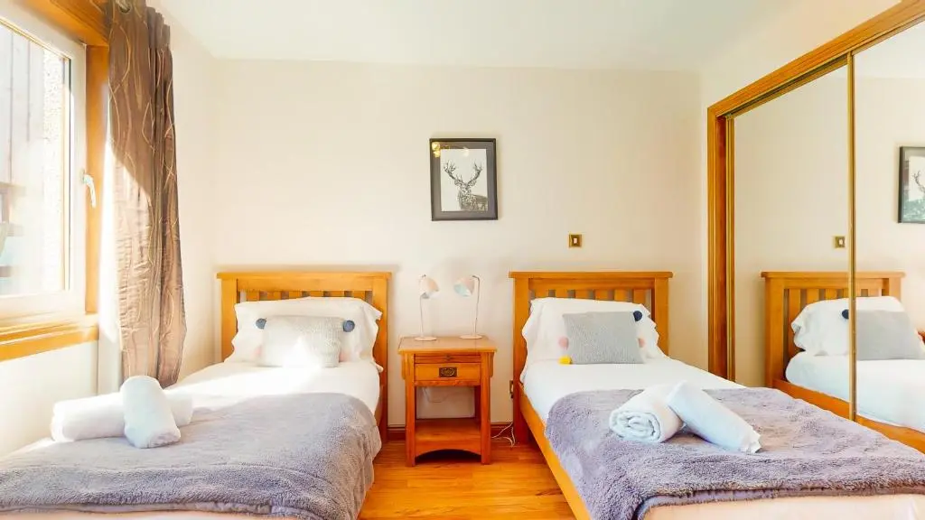 a bedroom with two twin beds and a mirror at The Shieling in Aviemore