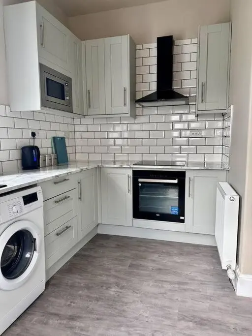 a kitchen with white cabinets and a washer and dryer at Home Sweet Home, Central in Inverness