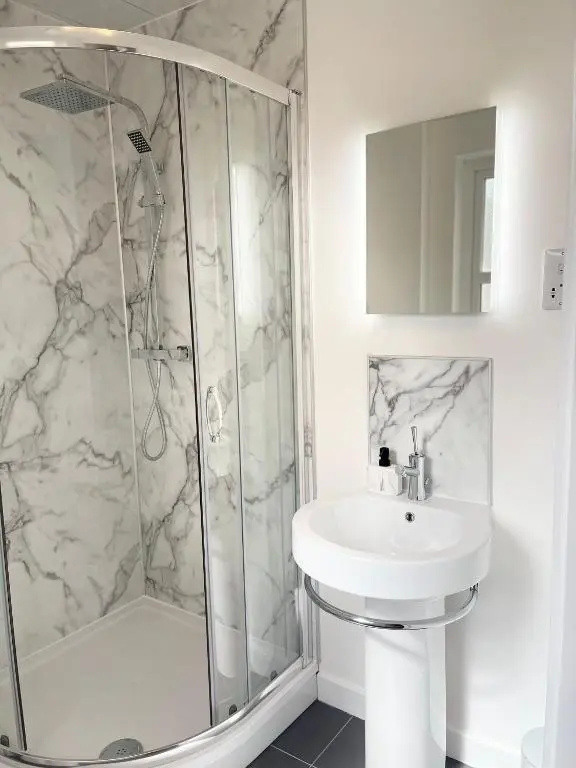 a white bathroom with a shower and a sink at Inverness Highland Apartment in Inverness