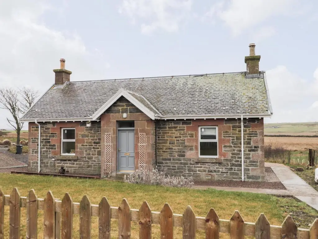 a brick house with a fence in front of it at Station House in Lybster