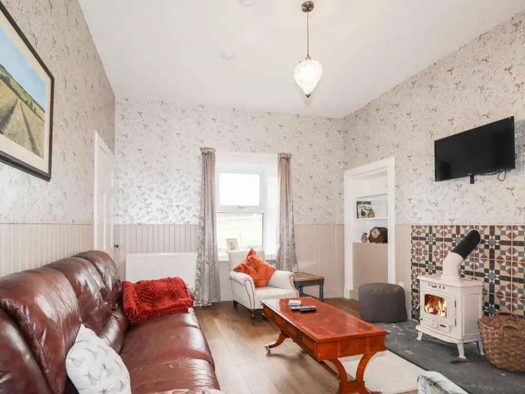 a living room with a leather couch and a fireplace at Station House in Lybster