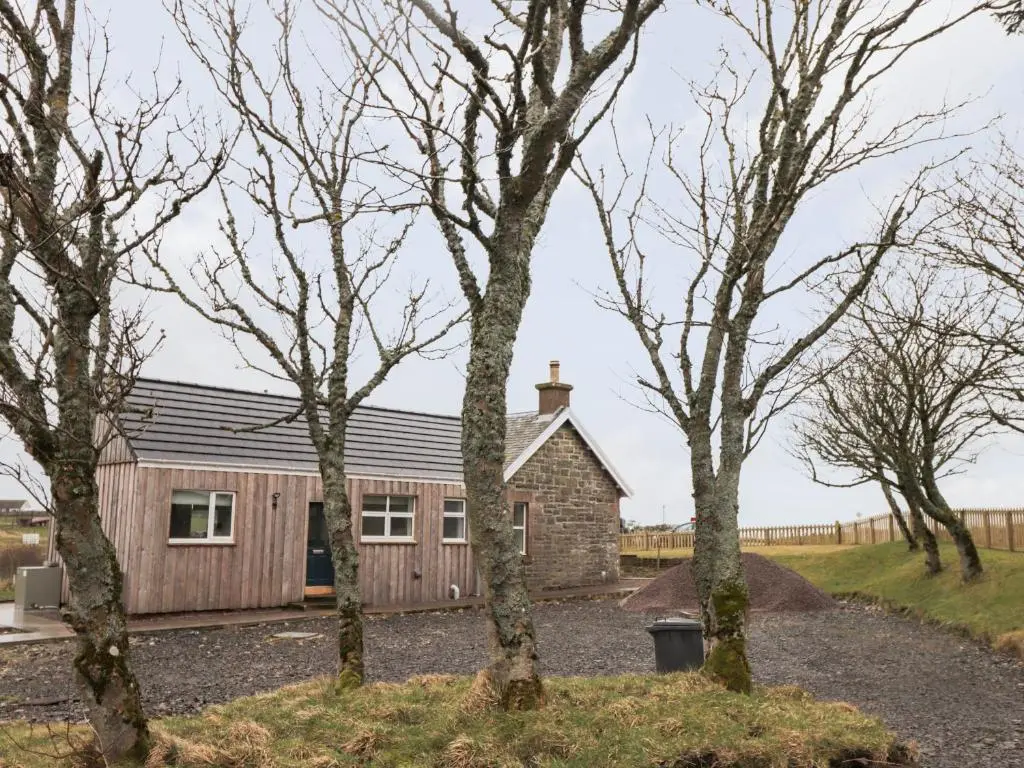 a barn conversion with trees in the foreground at Station House in Lybster
