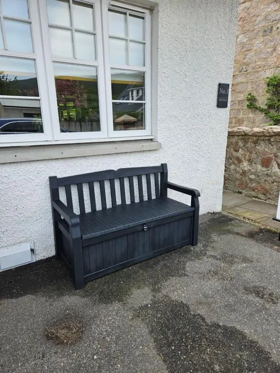 a black bench sitting outside of a building at 1 Golf Mews in Ballater